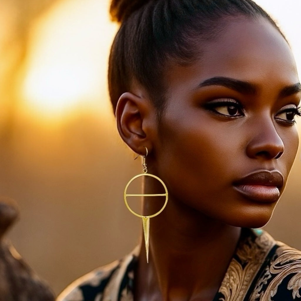 Woman with design gold circle and triangle drop dangle earrings against a warm, blurred background