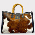 A tote bag with crocodile-like pattern on the leather, featuring bamboo handles and a detachable shoulder strap.
