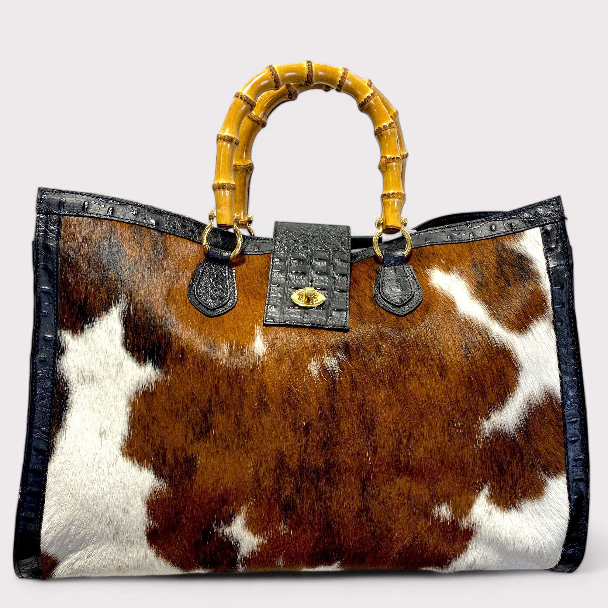A tote bag with crocodile-like pattern on the leather, featuring bamboo handles and a detachable shoulder strap.